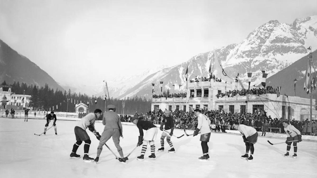 Black and white photo of people playing ice hockey.