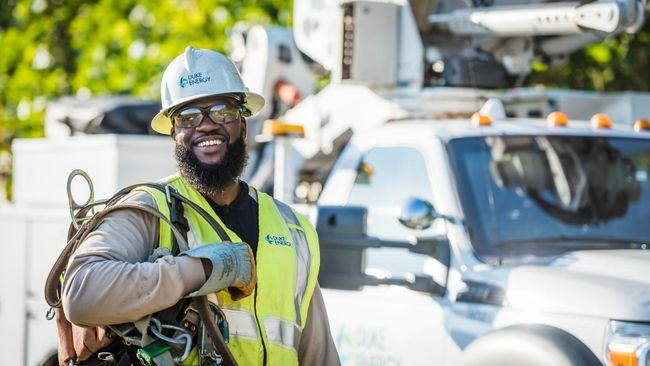 A smiling lineworker in front of a service truck.