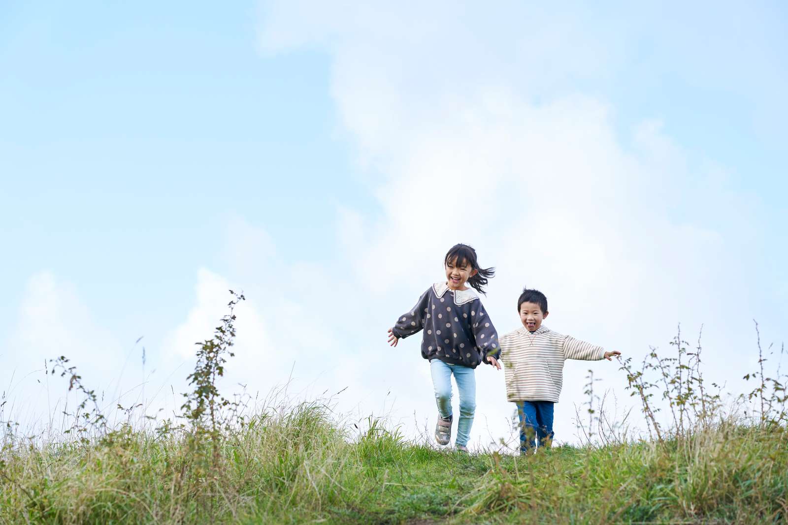 Two children running through grass