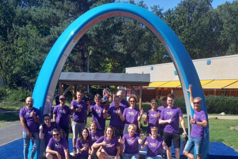Volunteers posed in front of a large blue arch outside. 