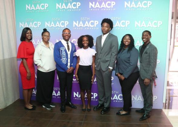 A group of people stood in front of a NAACP Image Awards event backdrop 