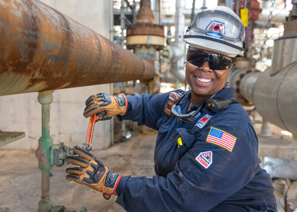 Dynita McCaskill turning a valve on an industrial pipe