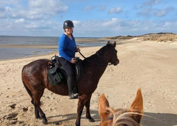 Julia Reilly riding a horse on a beach