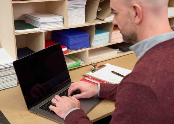 A person seated and in front of a laptop.