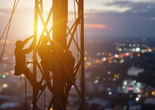 utility workers climb a tower