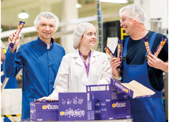 Three workers in their uniforms holding Mondelēz products