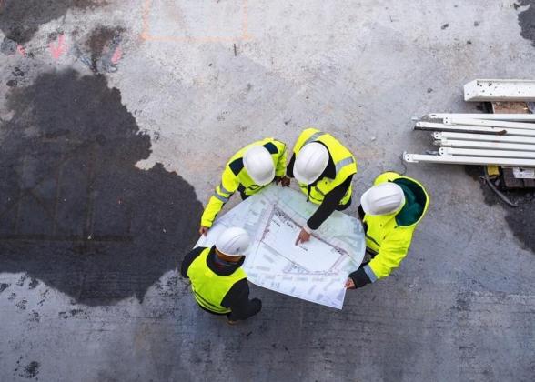 Aerial view of four construction workers overlooking a blueprint.