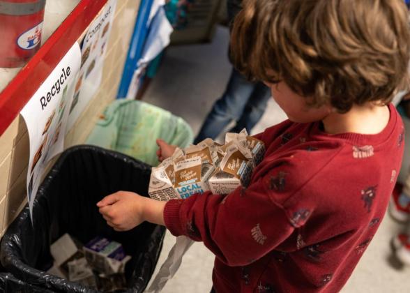 child recycling a carton