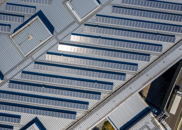 Aerial view of large rows of solar panels on a rooftop.
