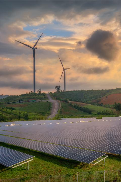 Clean Energy - Solar Panels and Wind Turbines in a field at sunset