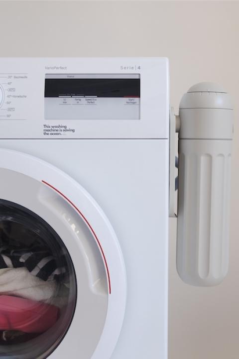 PlanetCare's microfiber filter attached to the side of a laundry machine.