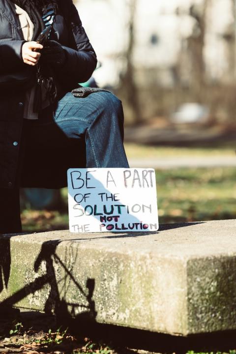Protestor holding sign that reads Be Part of the Solution Not Pollution