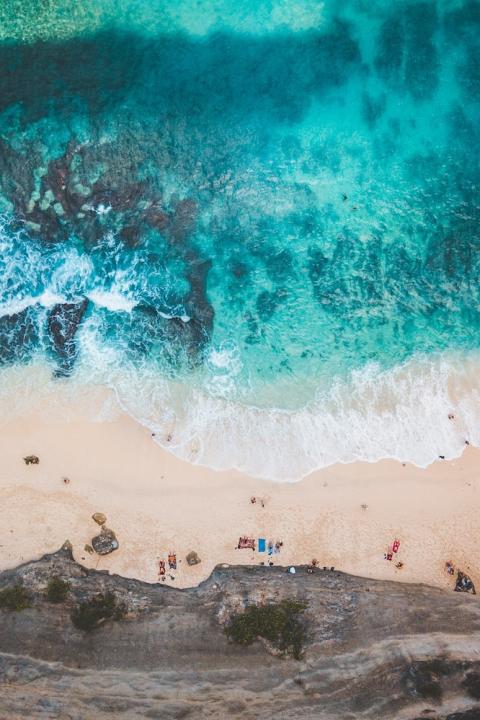 aerial view of ocean crashing on a beach shoreline - rising marine temperatures threaten ocean life