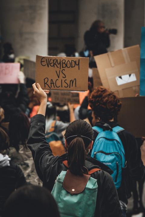 A protester holds a sign that says "Everybody vs racism." 