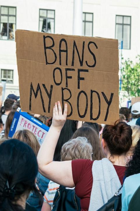 An activist holding a sign that reads, "Bans off my body." 