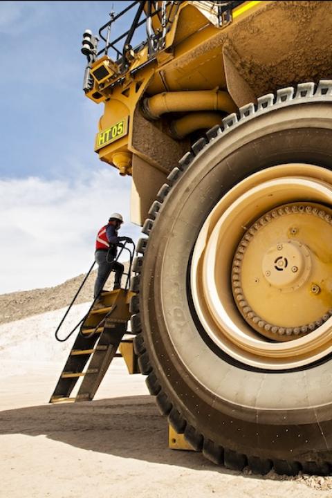 worker next to construction vehicle at a copper mine - human rights due diligence in the mining industry