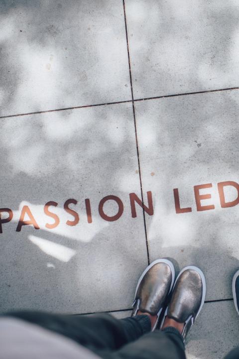 A photo looking down at a pair of shoes and the word "Passion".