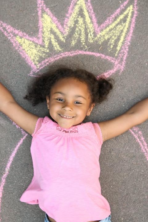 little girl laying on a chalk outline of a queen crown - chase your dreams
