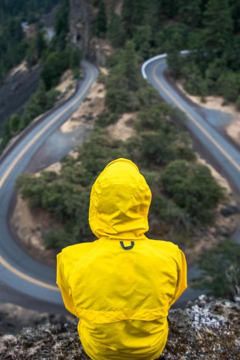 man in yellow parka looking down over roadway - ESG at a crossroads