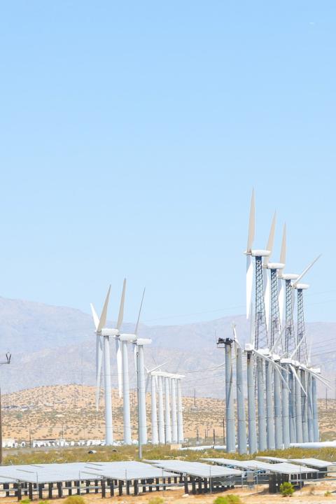 A photo showing wind turbines, solar panels and power lines - renewable energy