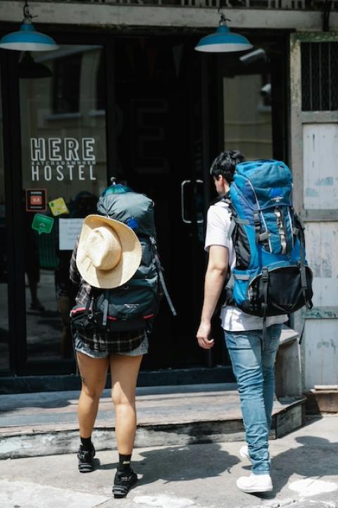 Two backpackers walking into a hostel. 