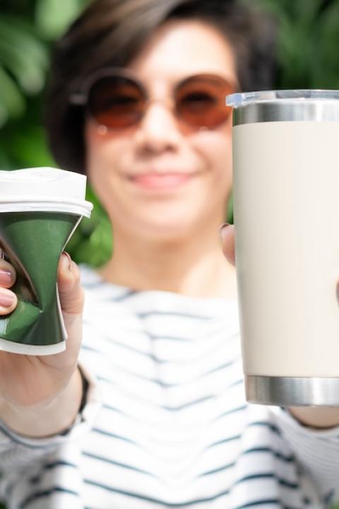 woman holding a single-use and reusable cup