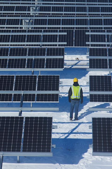 worker walks through shared michigan solar garden in the snow - community solar 