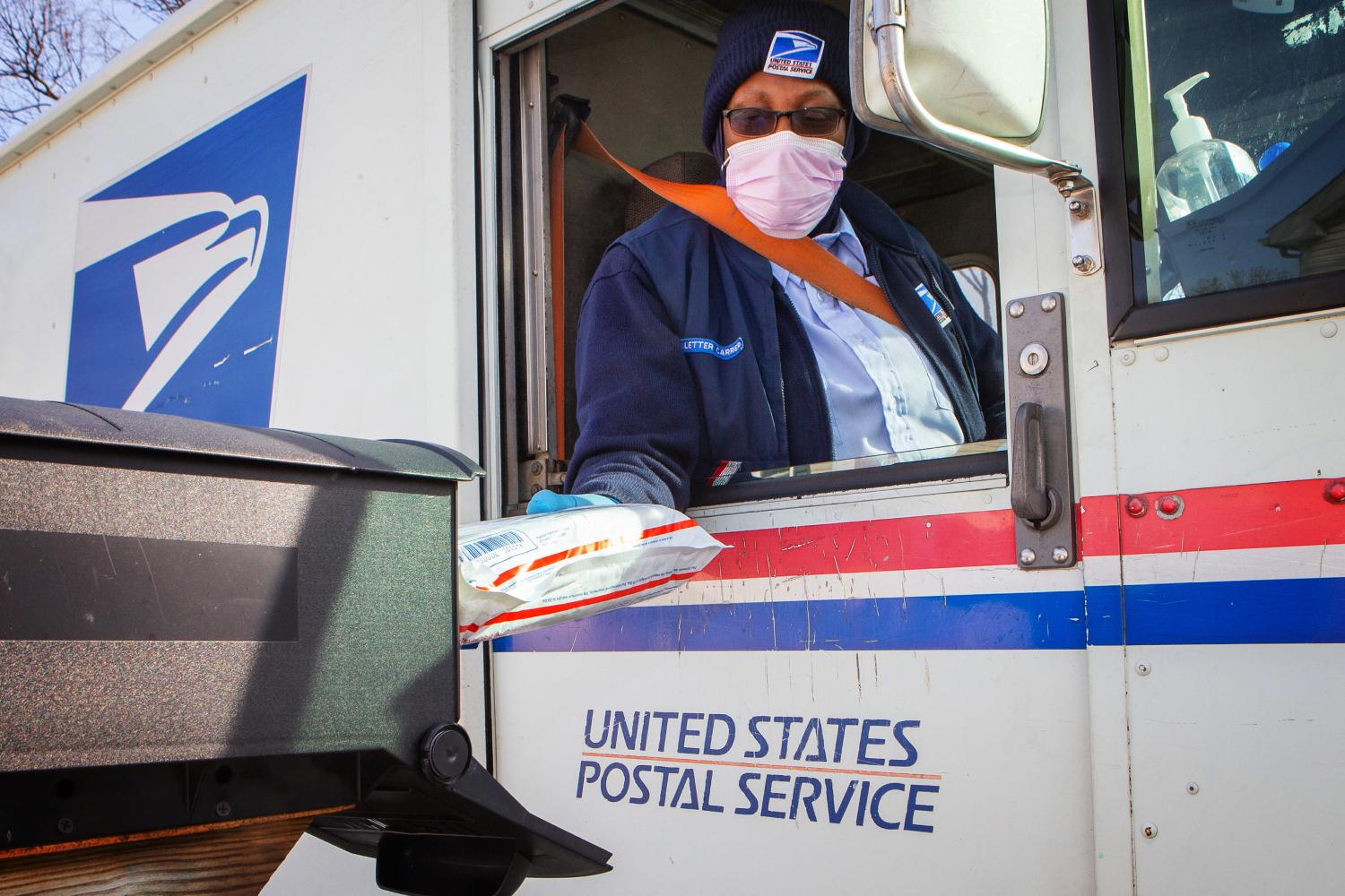 A U.S. Postal Service worker making a delivery from an agency truck. 
