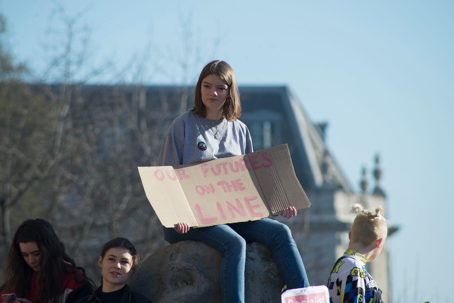 A protester with a sign that reads "Our future's on the line." — American Climate Corps
