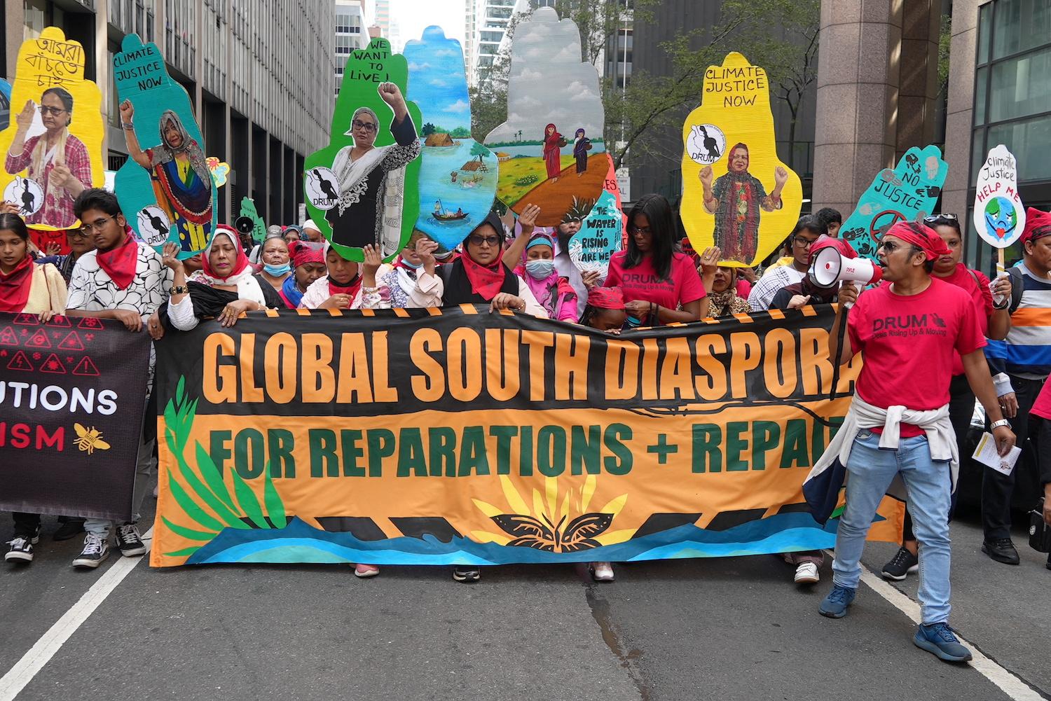 Activists hold a sign that reads "Global South Diaspora for Reparations + Repair" at a climate march.