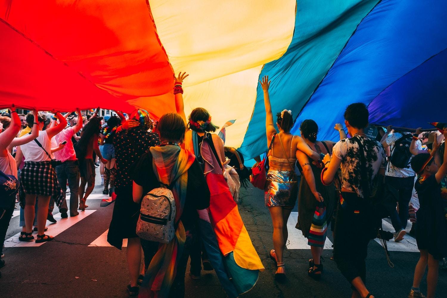 LGBTQ+ pride parade - people holding rainbow banner