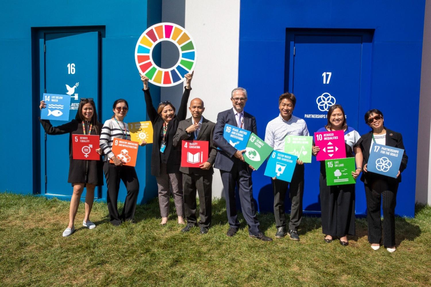 Leaders pose with blocks representing the SDGs at the SDG Pavilion Climate Week 2023