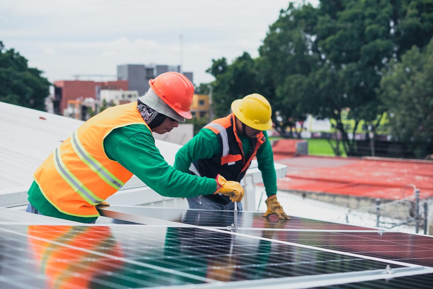 Solar power installers work on roof - clean energy jobs