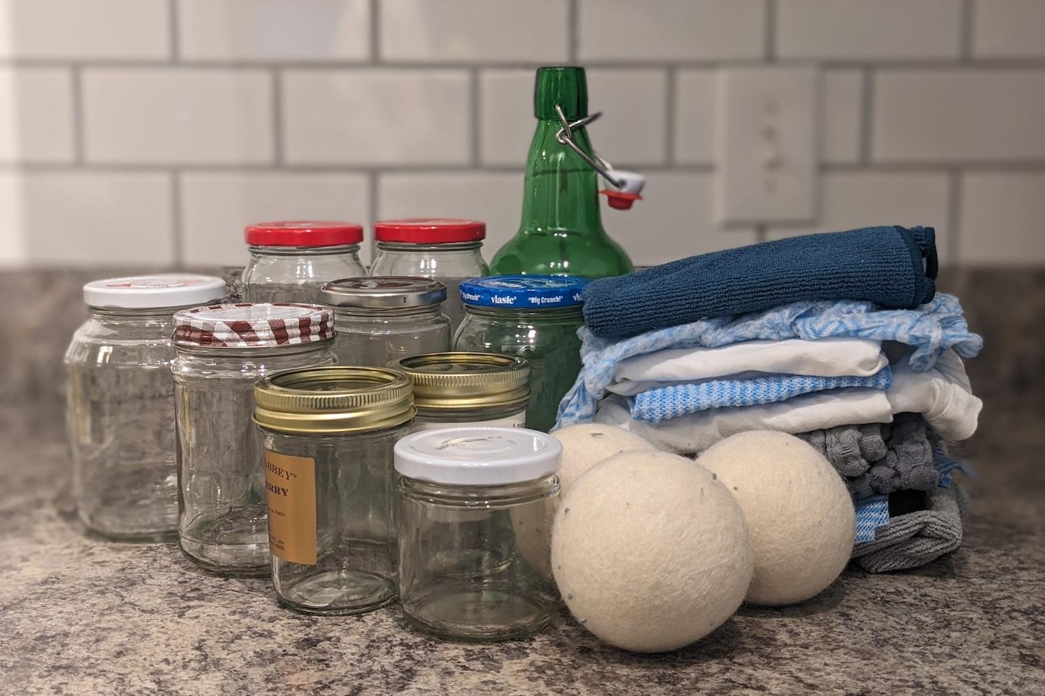 Collection of empty glass bottles, kitchen towels and wool dryer balls. 