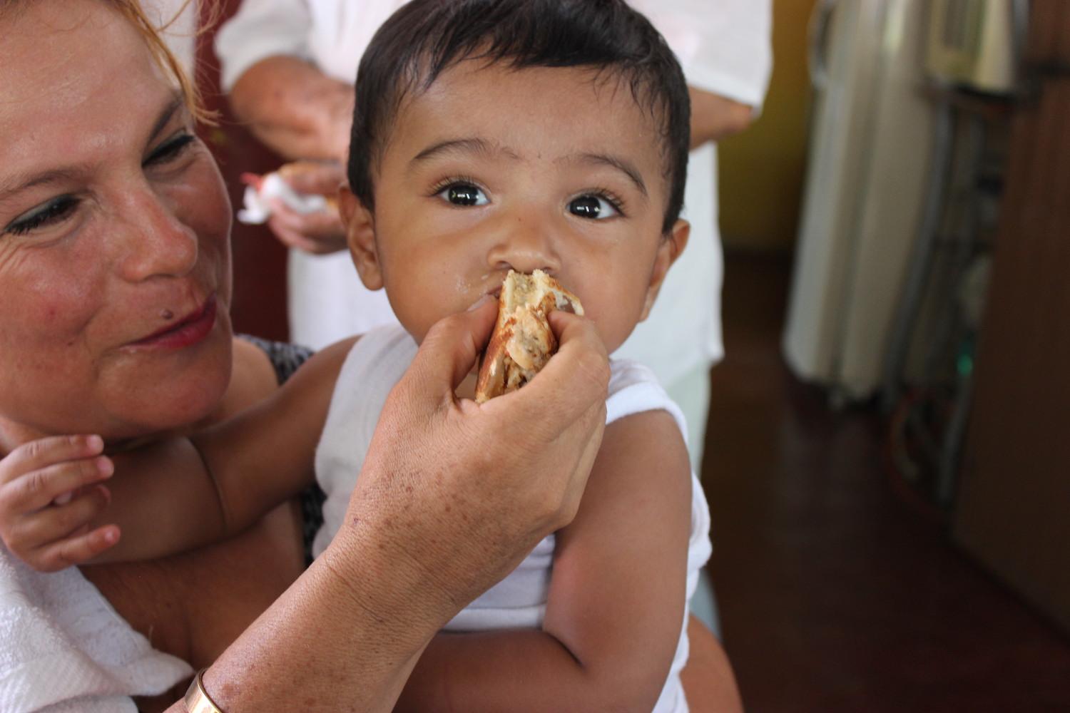 Woman feeding baby solid food - BAMX food bank network fights food insecurity in Mexico