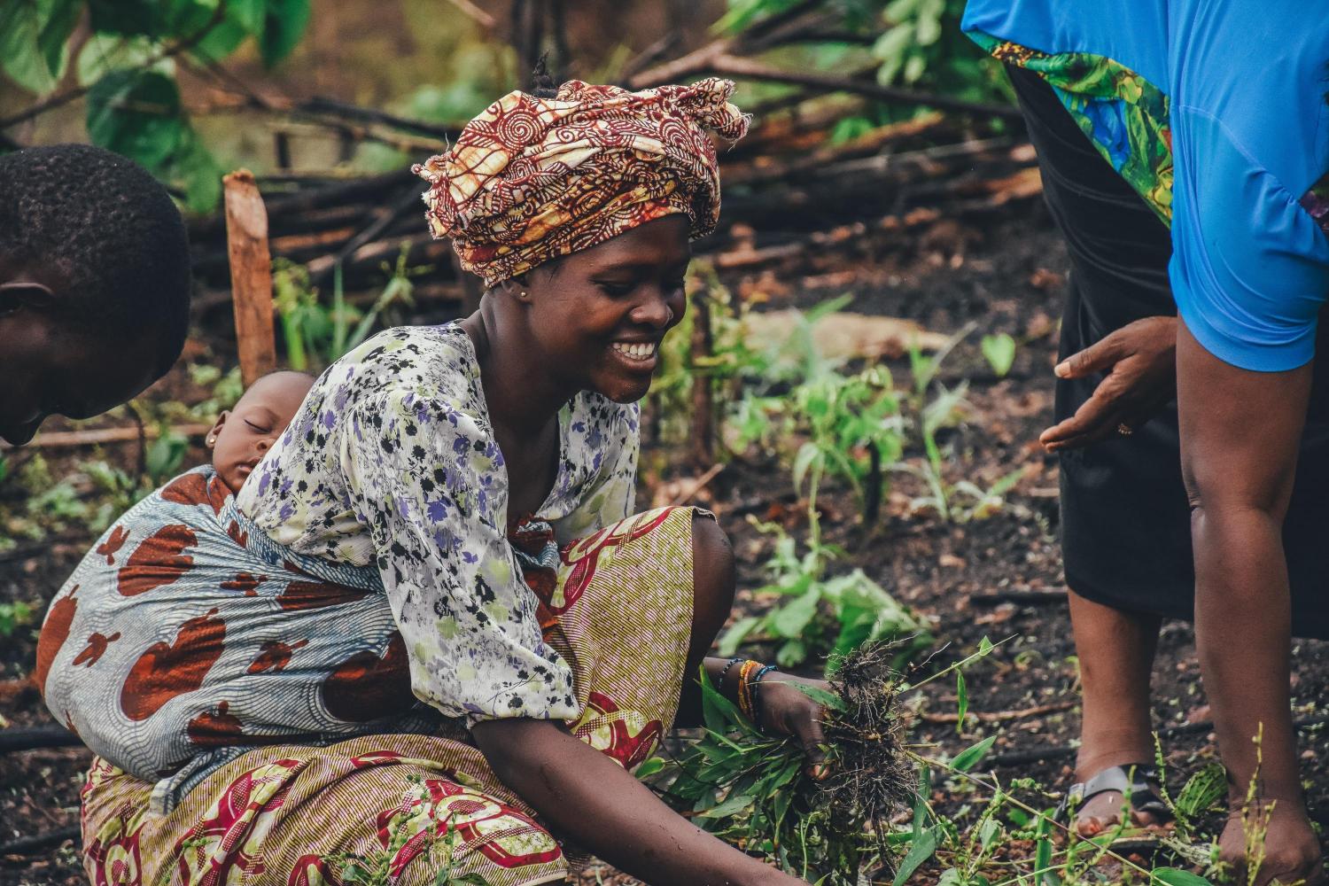 sustainable food systems - woman holding her baby while farming