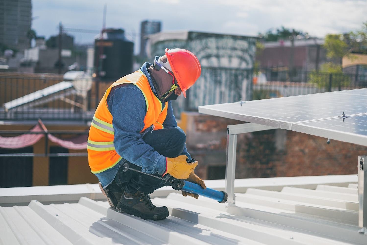 community solar - installer putting solar panels on rooftop in the city