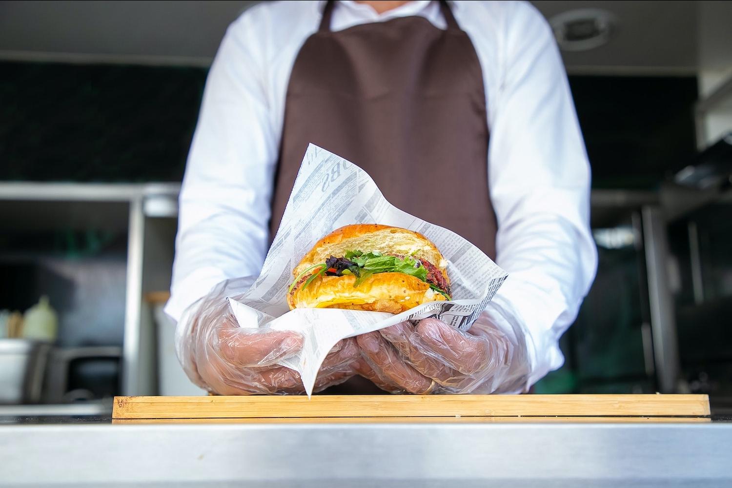 food cart owner holding burger in a wrapper