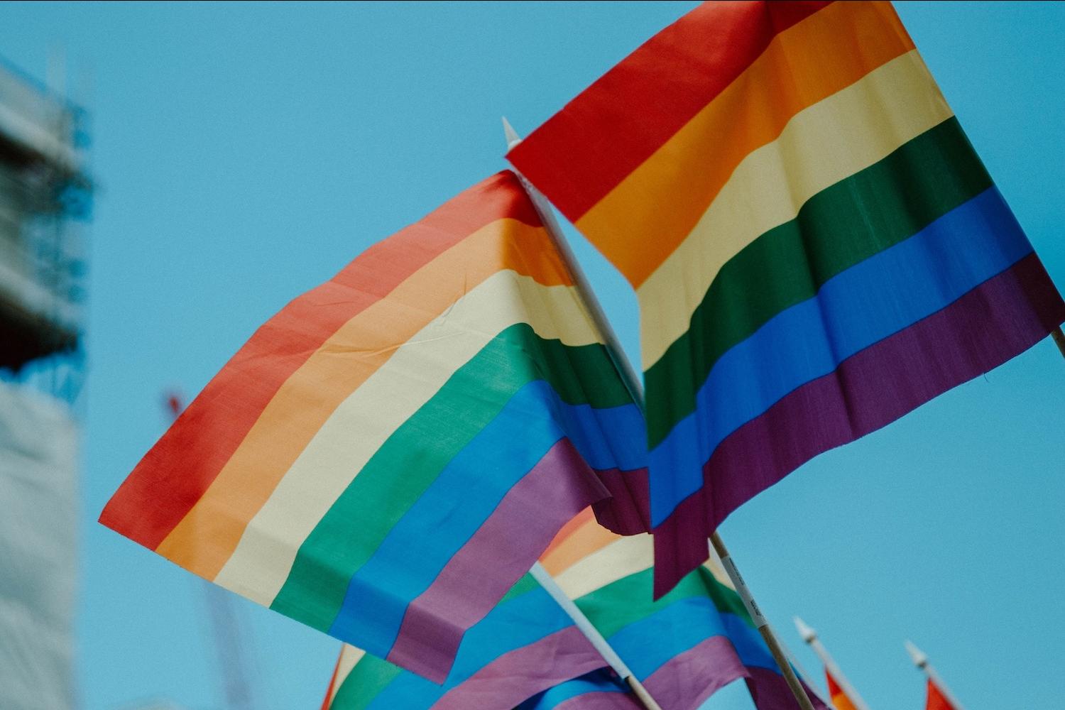 lgbtq+ pride flags against blue sky background