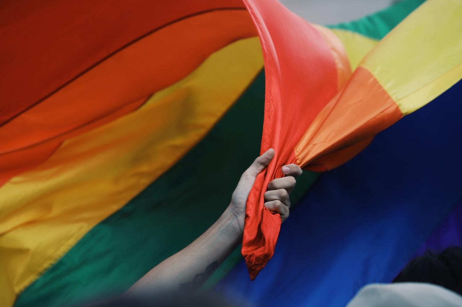 male hand holding rainbow pride flag - LGBTQ pride