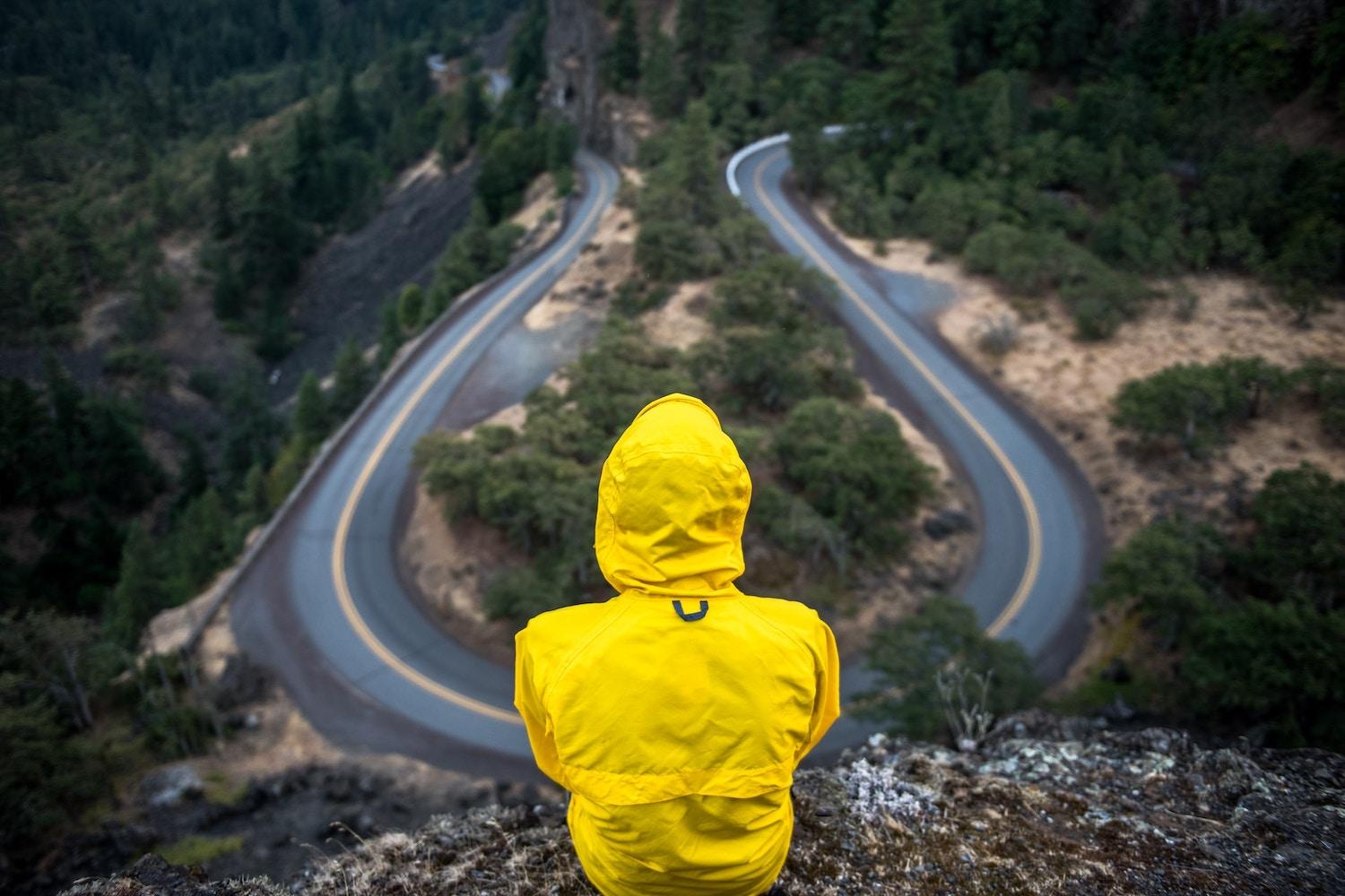 man in yellow parka looking down over roadway - ESG at a crossroads