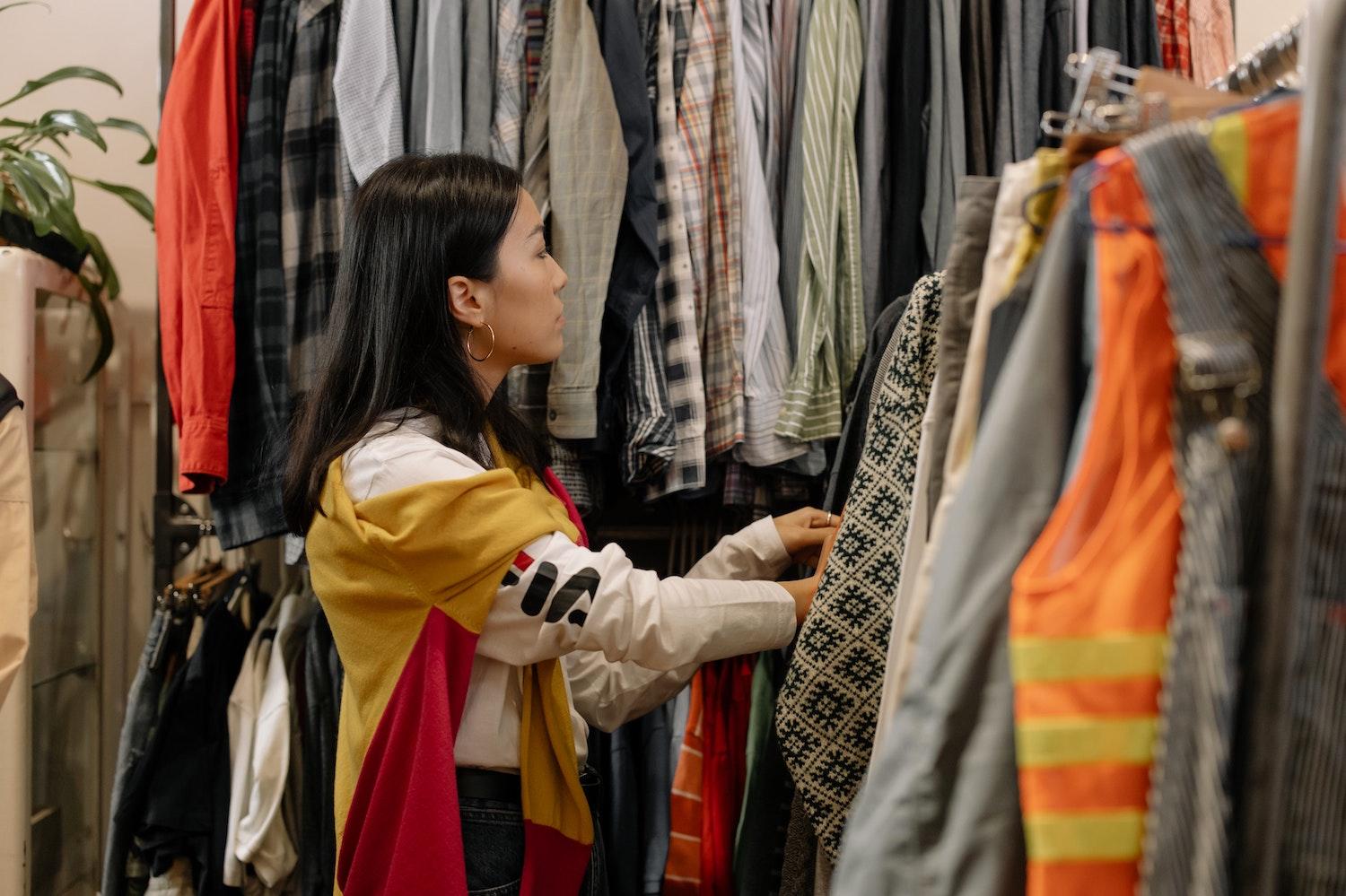 A shopper looks through clothes at a thrift store. 
