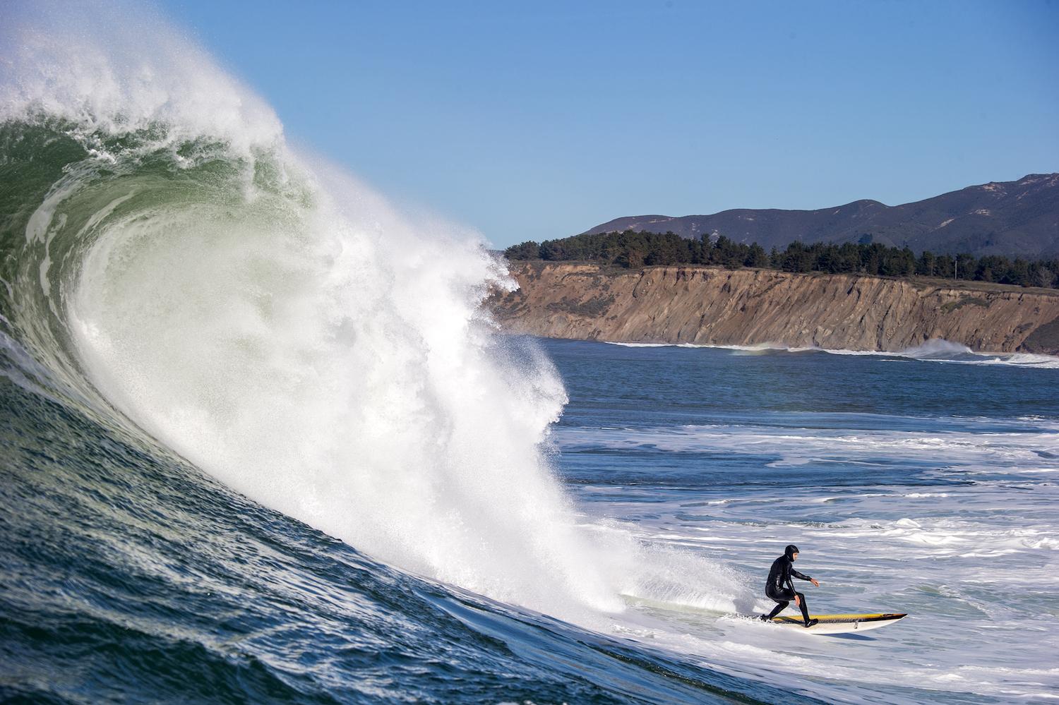 A person surfs in a Patagonia wetsuit at Half Moon Bay in California.