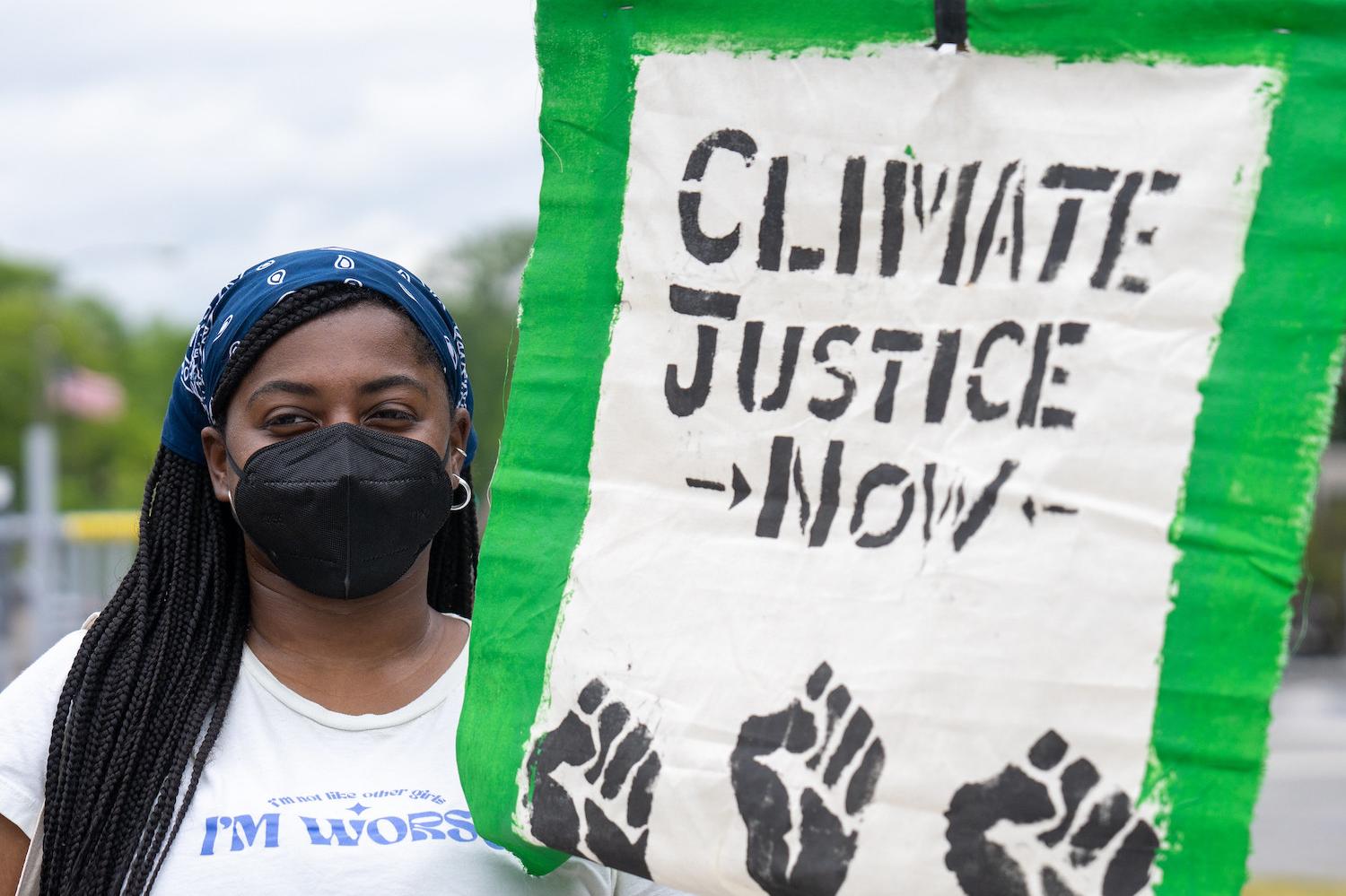 protestor holds sign reading climate justice now