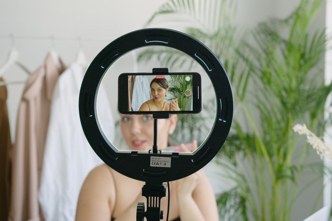 social media influencer content creator recording a video on a smartphone using a ring light - influencers can encourage sustainable consumer behavior change