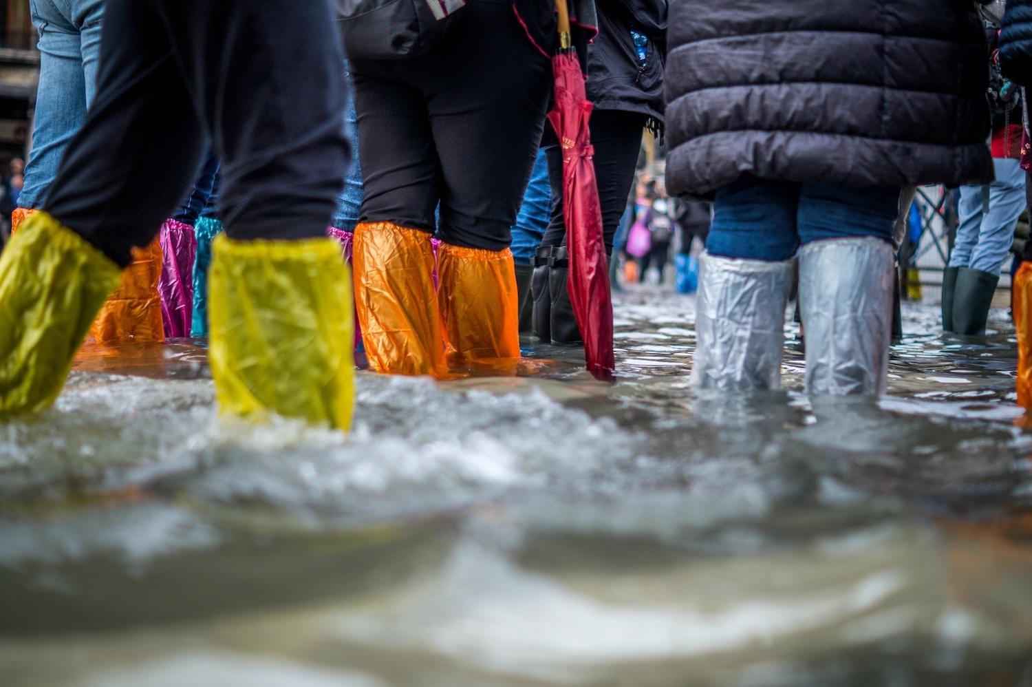 tourists try to stay dry during flooding in venice - disaster risks
