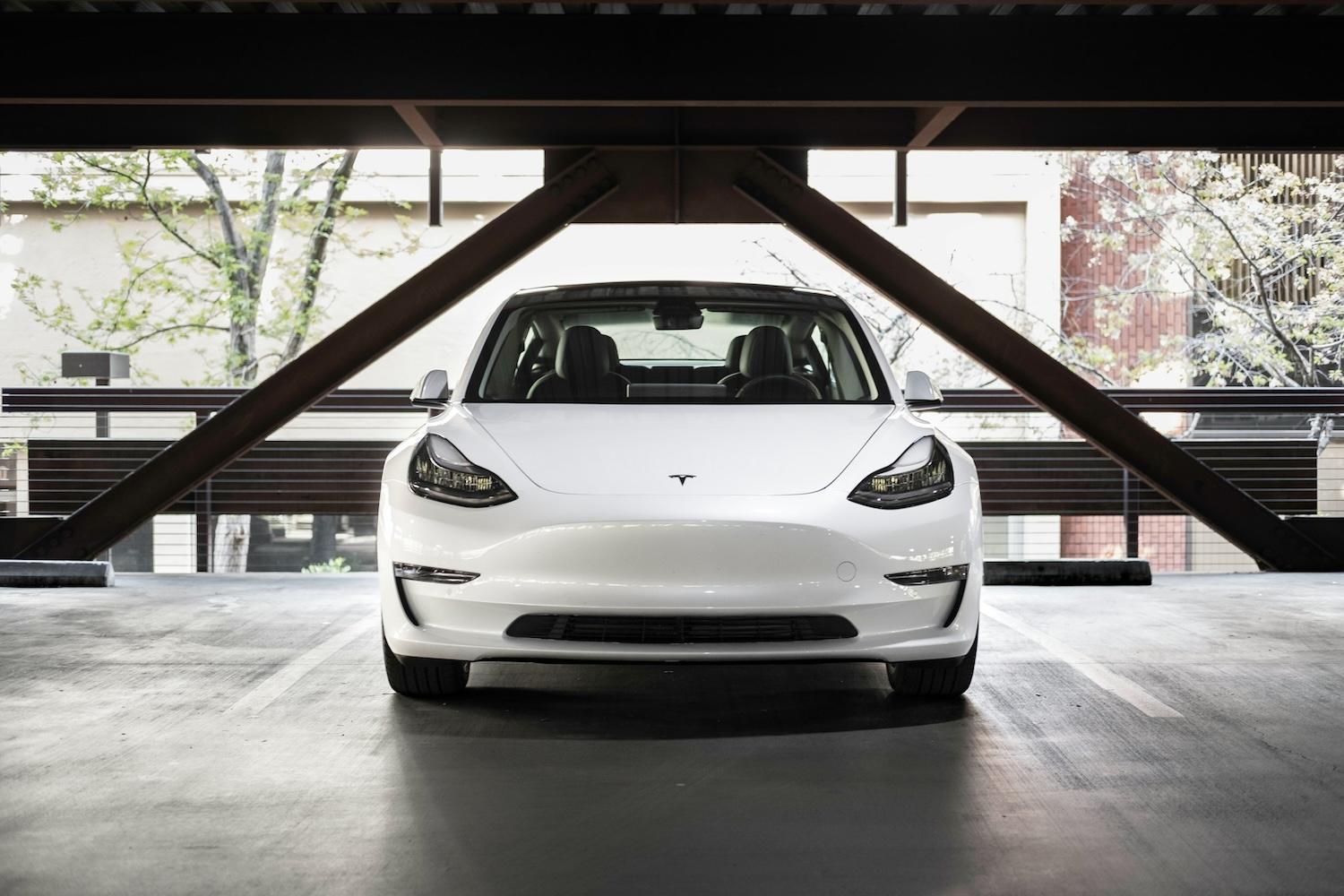 white tesla parked in parking garage