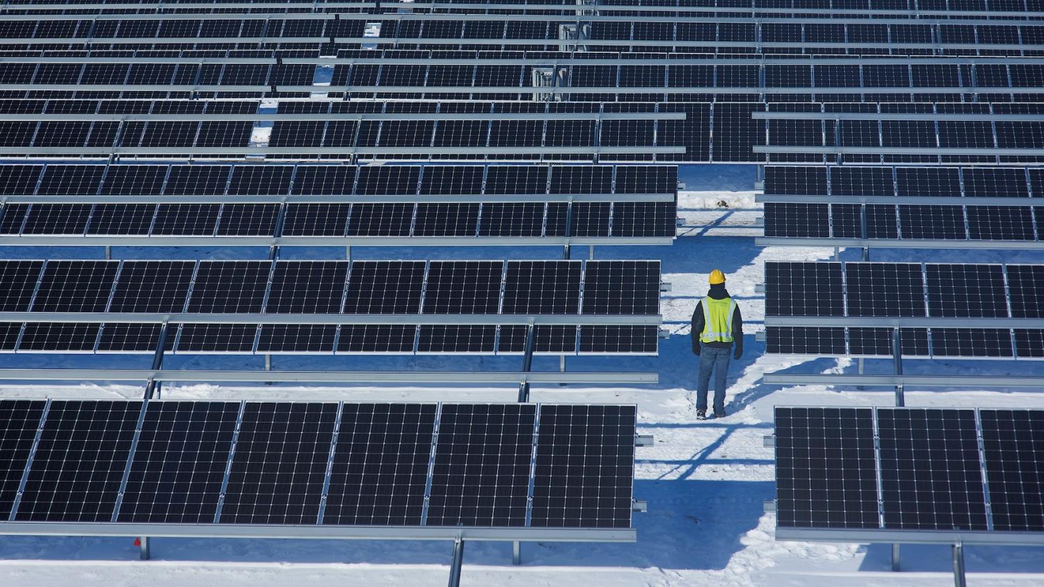 worker walks through shared michigan solar garden in the snow - community solar 