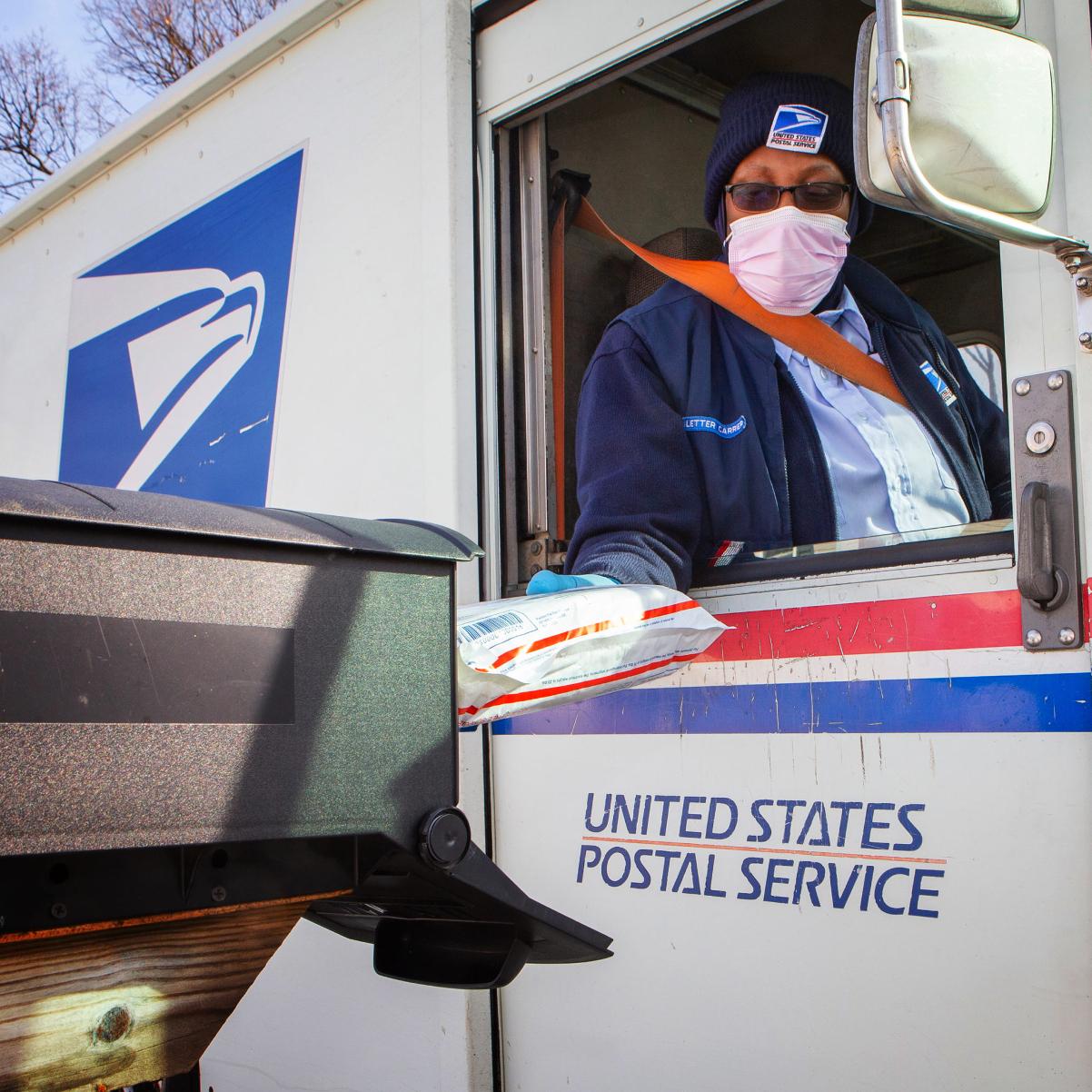 A U.S. Postal Service worker making a delivery from an agency truck.