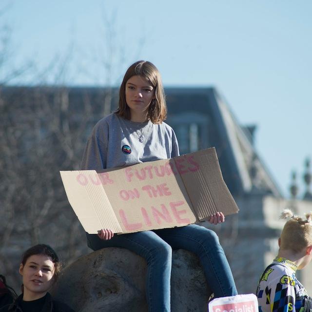 A protester with a sign that reads "Our future's on the line." — American Climate Corps